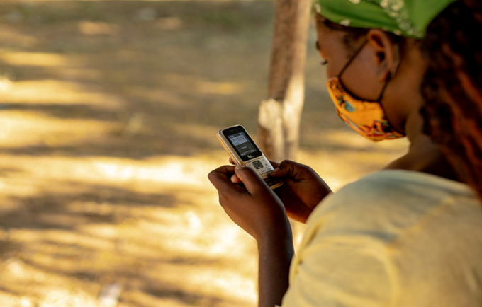Uma jovem mulher guarda números de linhas de apoio no seu telemóvel em Moçambique. Foto: UNFPA Moçambique / Mbuto Machili