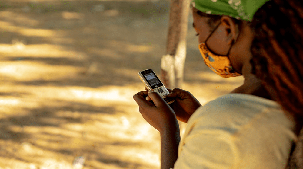 Uma jovem mulher guarda números de linhas de apoio no seu telemóvel em Moçambique. Foto: UNFPA Moçambique / Mbuto Machili