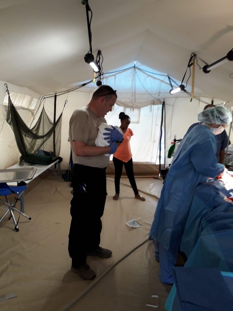 The newborn, in the arms of one of the medical team members.